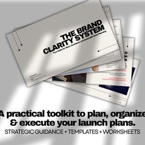 May include: A stack of white booklets with the title "THE BRAND CLARITY SYSTEM" in bold black letters. The text "Your Guide for Clear, Consistent, and Actionable Brand Planning" is below the title. The bottom of the image reads "A practical toolkit to plan, organize & execute your launch plans."