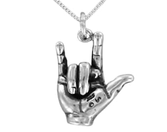 May include: A silver-toned pendant shaped like a hand making the I love you sign in American Sign Language, suspended from a delicate silver-toned chain. The pendant features detailed finger joints and a small engraved symbol on the palm area.