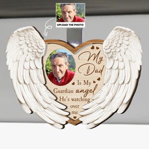 Peut inclure: Plaque commémorative en forme de cœur en bois avec des ailes d'ange. La plaque présente une photo d'un homme et le texte "My Dad Is My Guardian Angel He's watching over me." Comprend une petite zone de téléchargement de photos.