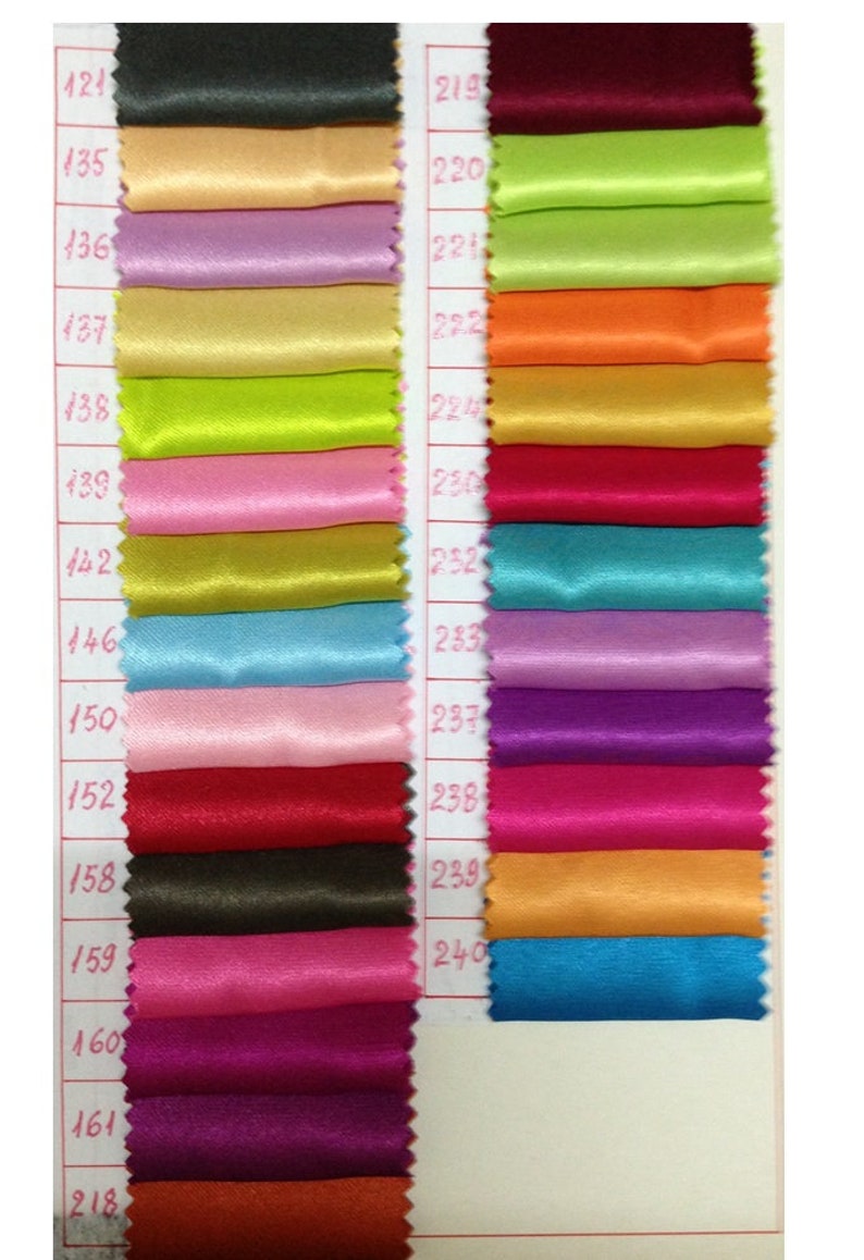 May include: A color swatch chart featuring various shades of satin fabric. The chart displays a range of colors, including black, beige, purple, green, pink, and blue. Each color is labeled with a number, providing a comprehensive color palette for design and craft projects.