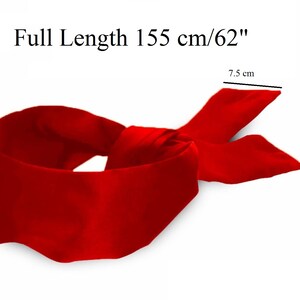 May include: A vibrant red satin blindfold with a full length of 62 inches and a width of 3 inches. The blindfold is tied in a knot, with the ends fanning out. The text "Full Length 155 cm/62" is visible.
