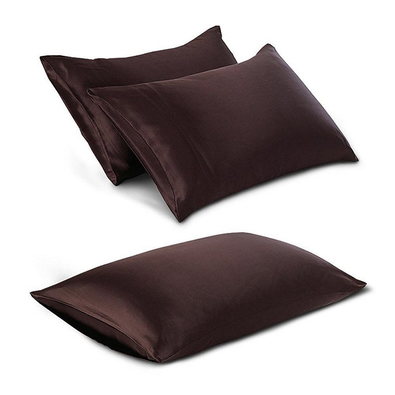 May include: Three dark brown satin pillowcases are shown against a white backdrop. Two pillowcases are stacked, and one is positioned below. The pillowcases have a smooth, shiny texture and a classic rectangular shape.