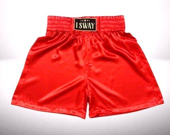 May include: Bright red satin boxing shorts with a wide elastic waistband. The waistband features the text "I SWAY" in a black rectangle. The shorts are designed with a classic boxing style, featuring a loose fit and a shiny finish.