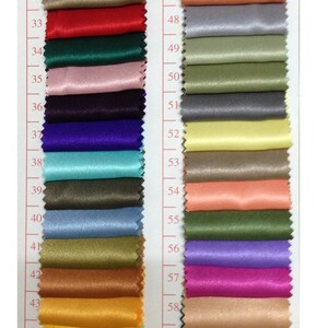 May include: A color swatch chart featuring a variety of fabric samples in a range of colors. The chart includes shades of black, red, green, pink, purple, blue, and gold. Each fabric sample is labeled with a number.