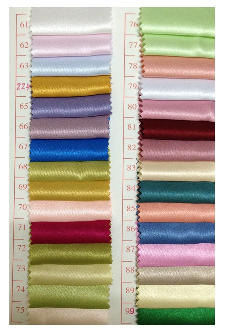 May include: A color swatch card featuring a variety of satin fabric samples. The samples are arranged in vertical rows, showcasing a spectrum of colors including white, pink, blue, gold, purple, and green. Each swatch is approximately 2 inches wide.
