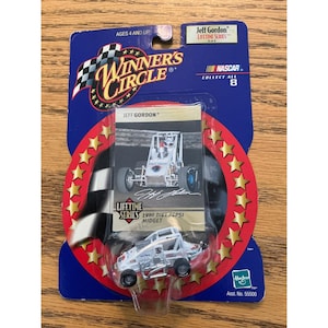 May include: A packaged Jeff Gordon 1990 Diet Pepsi Midget toy car. The card reads "Winner's Circle" and "NASCAR". The car is white with silver accents and black wheels. The packaging is blue, red, and gold.