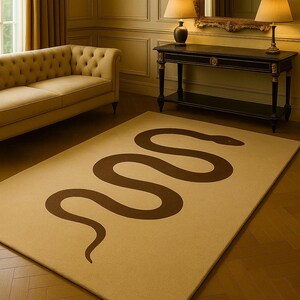 May include: Beige rectangular rug featuring a large, brown snake motif. The rug is positioned on a wooden floor within a room, alongside a sofa, table, and mirror. The room's ambiance is warm and inviting.