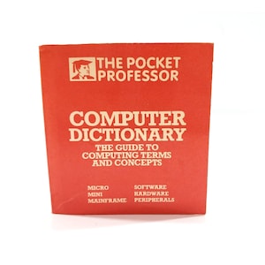 May include: A bright orange book titled The Pocket Professor Computer Dictionary: The Guide to Computing Terms and Concepts. The cover features a small graphic of a person wearing a graduation cap and lists topics including micro, mini, mainframe, software, hardware, and peripherals.