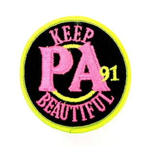 May include: A black and yellow round patch with the text "Keep PA Beautiful 91" in pink and yellow lettering.