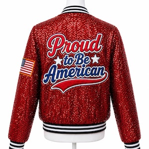 Pode incluir: Casaco vermelho com lantejoulas com as palavras "Proud to Be American" em letras brancas, vermelhas e azuis. Um patch da bandeira americana está na manga esquerda. O casaco tem acabamento listrado em preto e branco na gola, punhos e cintura.