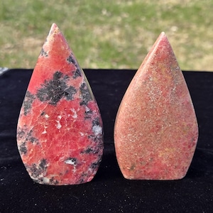 Pu&ograve; includere: Due pietre a forma di goccia. Una pietra &egrave; di un rosso vibrante con inclusioni nere e grigie. L'altra pietra &egrave; di un marrone rossastro smorzato. Entrambe le pietre hanno una superficie liscia e lucida e una parte superiore appuntita.