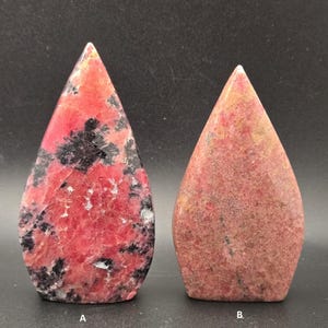 Pu&ograve; includere: Due pietre lucide a forma di goccia. La pietra A &egrave; di un rosso vibrante con inclusioni nere e venature bianche. La pietra B &egrave; di un rosso tenue con una texture maculata. Entrambe le pietre hanno una parte superiore appuntita.
