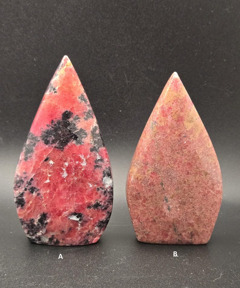 Pu&ograve; includere: Due pietre lucide a forma di goccia. La pietra A &egrave; di un rosso vibrante con inclusioni nere e venature bianche. La pietra B &egrave; di un rosso tenue con una texture maculata. Entrambe le pietre hanno una parte superiore appuntita.