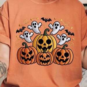 May include: Orange t-shirt featuring a Halloween design. The graphic includes jack-o'-lanterns, ghosts, and bats. The pumpkins are orange and yellow with carved faces. The ghosts are white, and the bats are black.