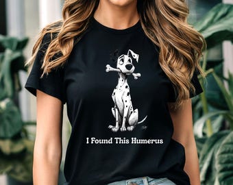 May include: Black t-shirt featuring a Dalmatian dog illustration holding a bone. The dog has black spots and is sitting upright. The text "I Found This Humerus" is printed below the dog.