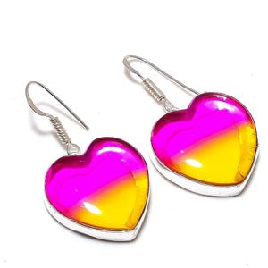 Könnte beinhalten: Ein Paar herzförmige Ohrringe mit einem Farbverlauf von Pink nach Gelb. Die Ohrringe haben einen silberfarbenen Metallrand und einen Hakenverschluss. Das herzförmige Design ist ein beliebter Schmuckstil.