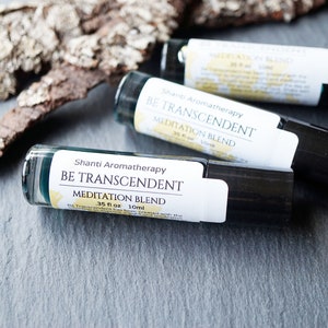 May include: Three small glass bottles with black roll-on tops. Each bottle has a white label with the text "Shanti Aromatherapy BE TRANSCENDENT MEDITATION BLEND 35 fl oz 10ml".