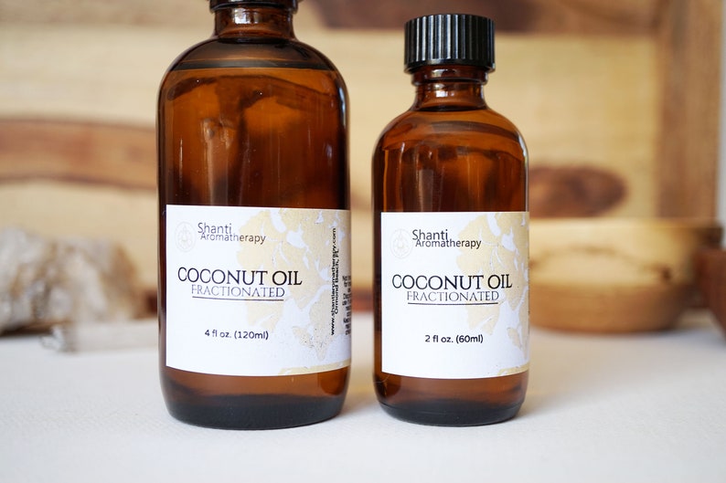 May include: Two amber glass bottles of fractionated coconut oil. The larger bottle is labeled 4 fl oz (120ml), and the smaller is 2 fl oz (60ml). Both have black caps and white labels with the text "Shanti Aromatherapy COCONUT OIL FRACTIONATED."