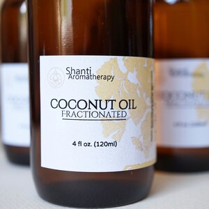 May include: Three brown glass bottles of fractionated coconut oil. Each bottle has a white label with the text "Shanti Aromatherapy" and "Coconut Oil Fractionated". The label also indicates the bottle contains 4 fl oz (120ml).