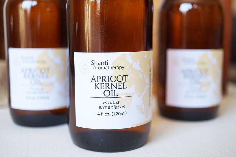 May include: A brown glass bottle with a white label that reads "Shanti Aromatherapy Apricot Kernel Oil Prunus armeniacus 4 fl oz. (120ml)"