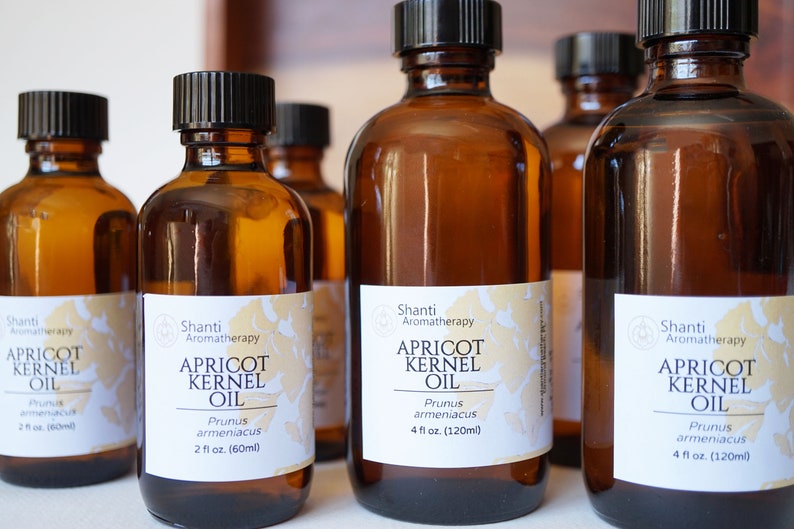 May include: Five amber glass bottles of apricot kernel oil, each with a white label that reads "Shanti Aromatherapy Apricot Kernel Oil Prunus armeniacaus" and the size of the bottle in fluid ounces.