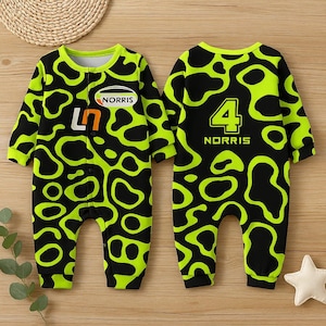May include: A baby's jumpsuit with a black and neon green pattern. The front features the text "NORRIS" and the number "47". The back of the jumpsuit has the number "4" and the name "NORRIS". The jumpsuit has long sleeves and a round neckline.