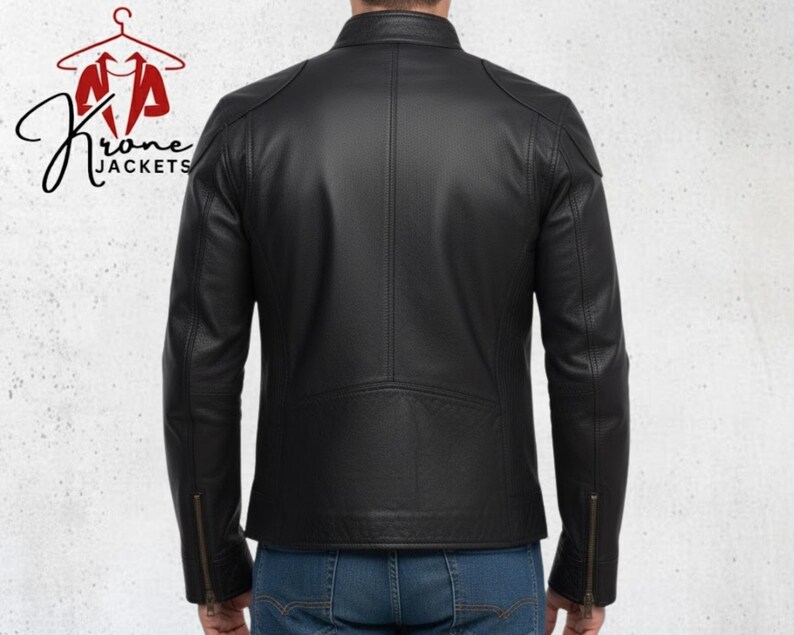 K&ouml;nnte beinhalten: Schwarze Lederjacke mit Stehkragen und Rei&szlig;verschlussdetails an den &Auml;rmeln. Die Jacke hat ein gestepptes Design an Schultern und unterem R&uuml;cken. Das Logo "Krone Jackets" ist oben links sichtbar.