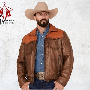 Op de afbeelding: Een bruine leren jas met een contrasterende bruine pas en zakken. De jas wordt gedragen over een spijkerblouse en jeans. Een cowboyhoed en gesp maken de westernlook compleet. Het logo "Krone Jackets" is zichtbaar in de linkerbovenhoek.