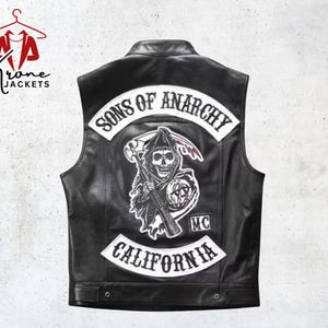 May include: Black leather vest with the "Sons of Anarchy" logo on the back. The logo features a grim reaper with a scythe, the words "Sons of Anarchy" and "California" in white lettering. The vest has a classic biker style.
