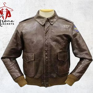 Puede incluir: Chaqueta de cuero marr&oacute;n con dos bolsillos delanteros, cuello y pu&ntilde;os acanalados. La chaqueta tiene un parche en la manga superior izquierda. La chaqueta se exhibe en un maniqu&iacute;. El logotipo "Krone Jackets" est&aacute; en la esquina superior izquierda.