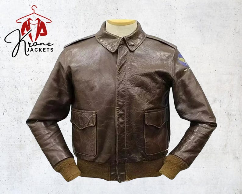 Puede incluir: Chaqueta de cuero marr&oacute;n con dos bolsillos delanteros, cuello y pu&ntilde;os acanalados. La chaqueta tiene un parche en la manga superior izquierda. La chaqueta se exhibe en un maniqu&iacute;. El logotipo "Krone Jackets" est&aacute; en la esquina superior izquierda.