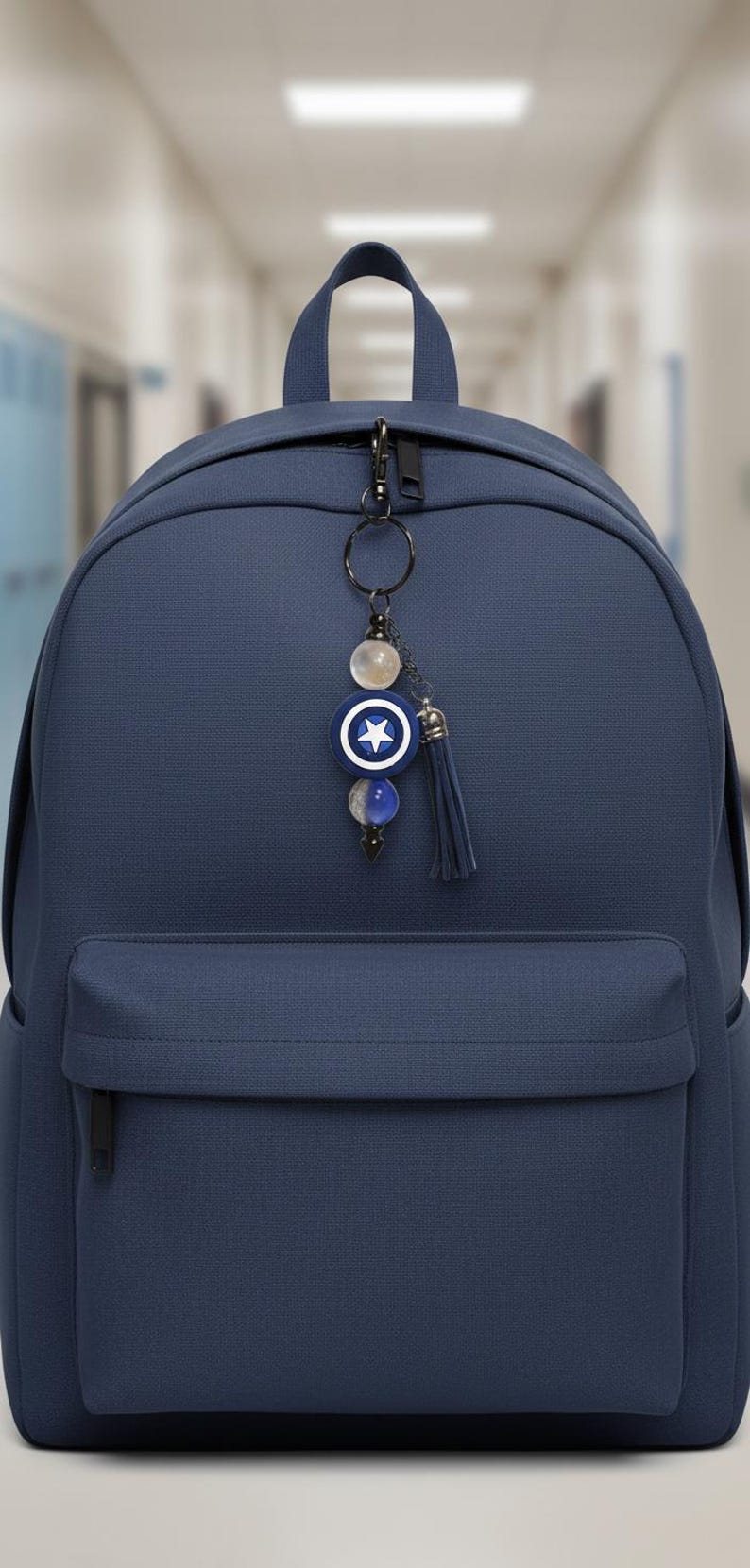 May include: A navy blue backpack with a decorative keychain. The keychain features a blue and white star emblem, beads, and a navy tassel. The backpack has a front pocket and a top handle.