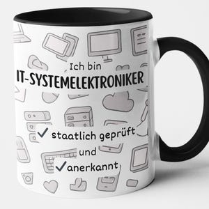Op de afbeelding: Witte keramische mok met een zwarte binnenkant en handvat. De mok heeft een herhalend patroon van computergerelateerde krabbels en de tekst "Ich bin IT-Systemelektroniker" in het zwart. De tekst "staatlich geprüft und anerkannt" is ook zichtbaar.