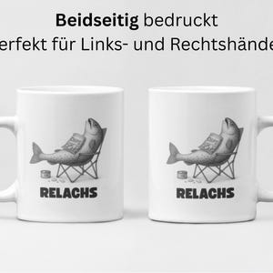 May include: Two white ceramic mugs with a humorous illustration of a fish relaxing in a folding chair, holding a bag of chips. The word "RELACHS" is printed below the image. The text "Beidseitig bedruckt Perfekt f&uuml;r Links- und Rechtsh&auml;nder" is printed above the image.