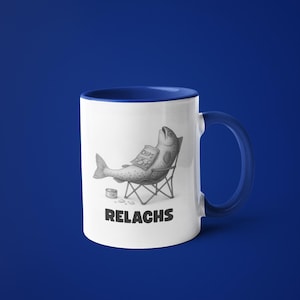 May include: White ceramic mug with a blue interior and handle. The mug features a humorous illustration of a fish relaxing in a folding chair, holding a bag of chips. The word "RELACHS" is printed below the image.
