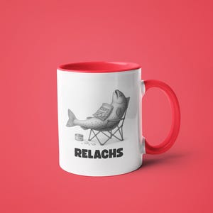 May include: White ceramic mug with a red interior and handle. The mug features a humorous illustration of a fish relaxing in a beach chair, holding a bag of chips. The word "RELACHS" is printed below the illustration.