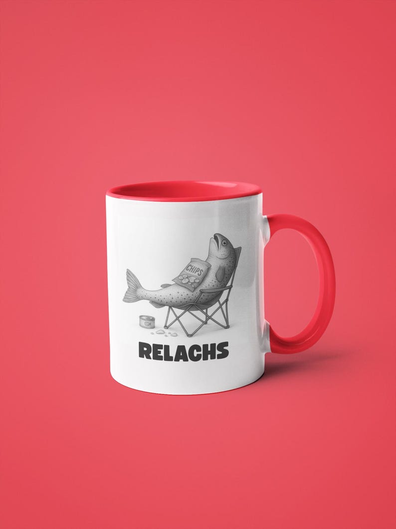 May include: White ceramic mug with a red interior and handle. The mug features a humorous illustration of a fish relaxing in a beach chair, holding a bag of chips. The word "RELACHS" is printed below the illustration.