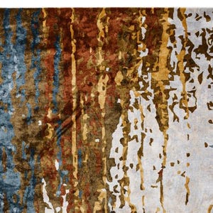 May include: Abstract area rug with a distressed design. The rug features a blend of colors, including blue, brown, gold, and white, creating a textured, artistic appearance. The design has vertical and scattered elements.