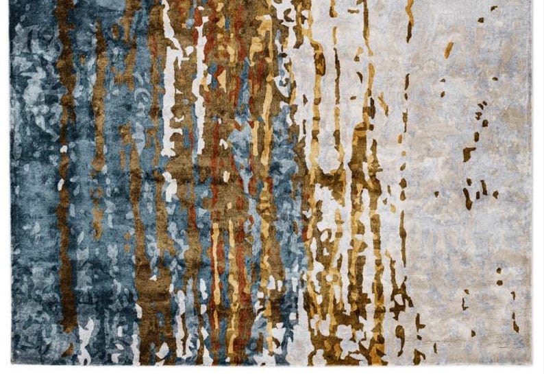 May include: A rectangular area rug with an abstract design. The rug features a blend of colors, including blue, brown, and white, with vertical, textured patterns. The design creates a modern and artistic look, suitable for home decor.