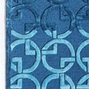 May include: A rectangular blue rug with a repeating pattern of interlocking circles and squares. The design is a lighter shade of blue than the rug's background. The rug has a soft, textured appearance.
