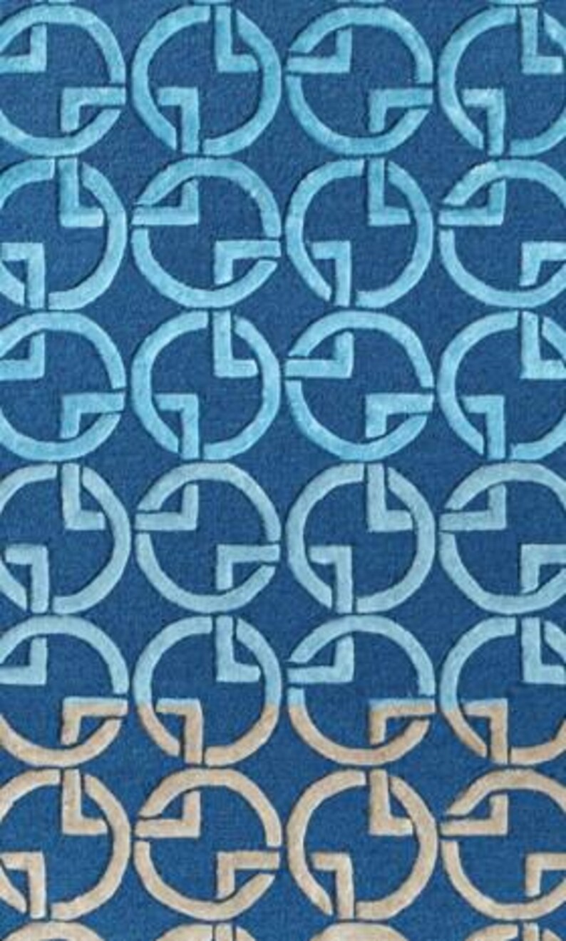 May include: A blue rug with a repeating pattern of interlocking circles and cross-like shapes. The design features varying shades of blue and a touch of beige, creating a textured, geometric aesthetic. The rug's design is suitable for home decor.