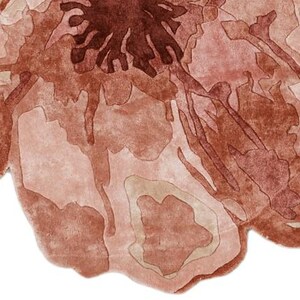 May include: A watercolor painting of a flower in shades of brown and pink. The petals have a layered effect, with darker brown details in the center and lighter pink hues towards the edges. The background is white.