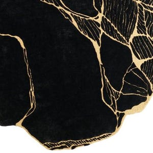 May include: A black rug with a unique, organic shape. The rug features a striking design of gold-colored veins and leaf-like patterns against a solid black background. The rug's design adds a touch of modern elegance to any room.