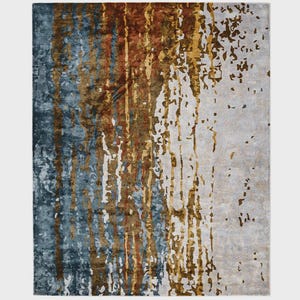 May include: A rectangular area rug with an abstract design. The rug features vertical streaks of blue, brown, and gold against a neutral background. The design has a textured appearance, creating a modern aesthetic.