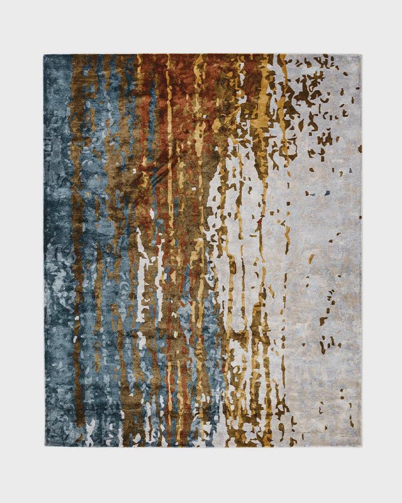 May include: A rectangular area rug with an abstract design. The rug features vertical streaks of blue, brown, and gold against a neutral background. The design has a textured appearance, creating a modern aesthetic.
