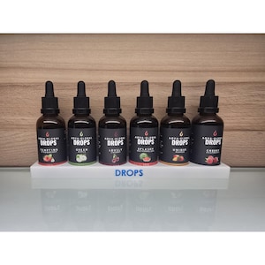 May include: Six glass dropper bottles with black caps and labels, arranged on a white shelf. The labels read "AQUA-GLOBAL DROPS" with various fruit names like "Tempting Strawberry" and "Cheeky Raspberry". The shelf has the word "DROPS" printed on it.