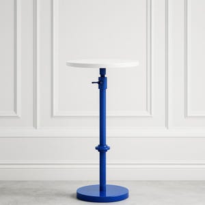 May include: A modern, adjustable side table with a round white tabletop. The table features a vibrant blue, adjustable central column and a matching circular base. The table's height is adjustable, offering versatility for various uses.