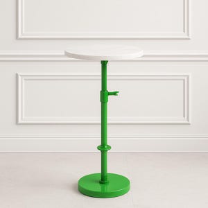 Puede incluir: Una mesa auxiliar moderna y ajustable con una tapa redonda blanca y una base y un tallo de color verde brillante. El tallo tiene un mecanismo de ajuste de altura. La base de la mesa es de forma circular. Para uso en interiores.