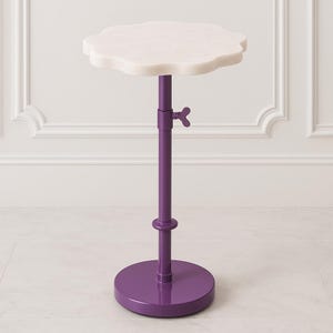 May include: A small, adjustable side table with a white, cloud-shaped marble top. The table has a vibrant purple, adjustable stem and a round base. The height is adjustable with a butterfly-shaped knob. A stylish accent piece for any room.