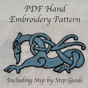 May include: A hand embroidery pattern showing a blue stylized creature with black outlines, stitched on a light fabric. The text "PDF Hand Embroidery Pattern" and "Including Step by Step Guide" are displayed in black script.